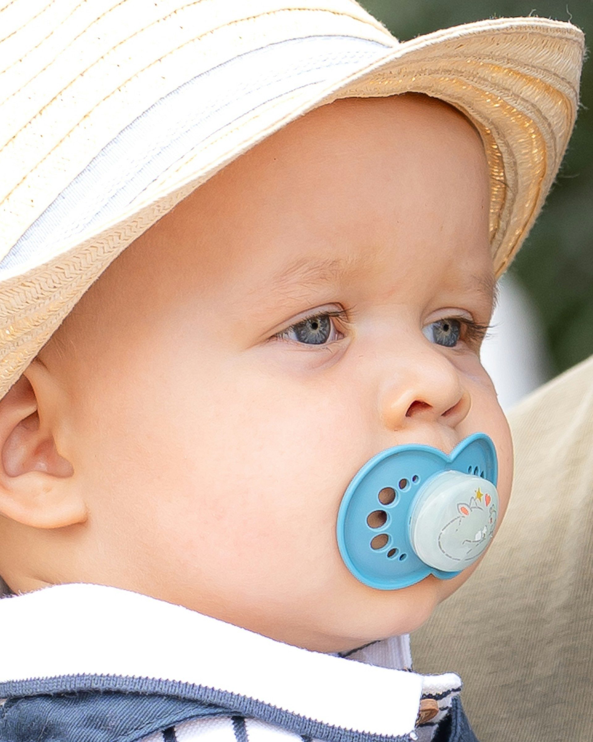 Baby in a straw sun hat with a dummy