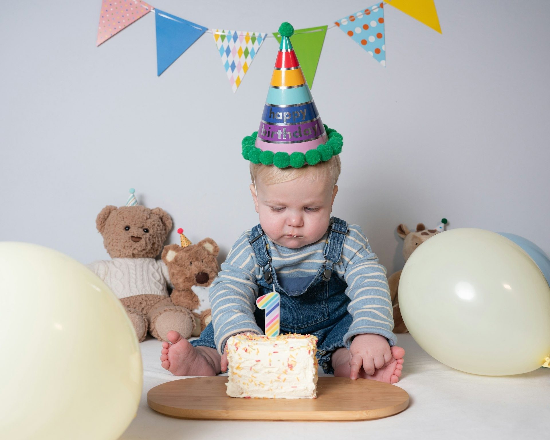 Toddler studies the candle on his birthday cake