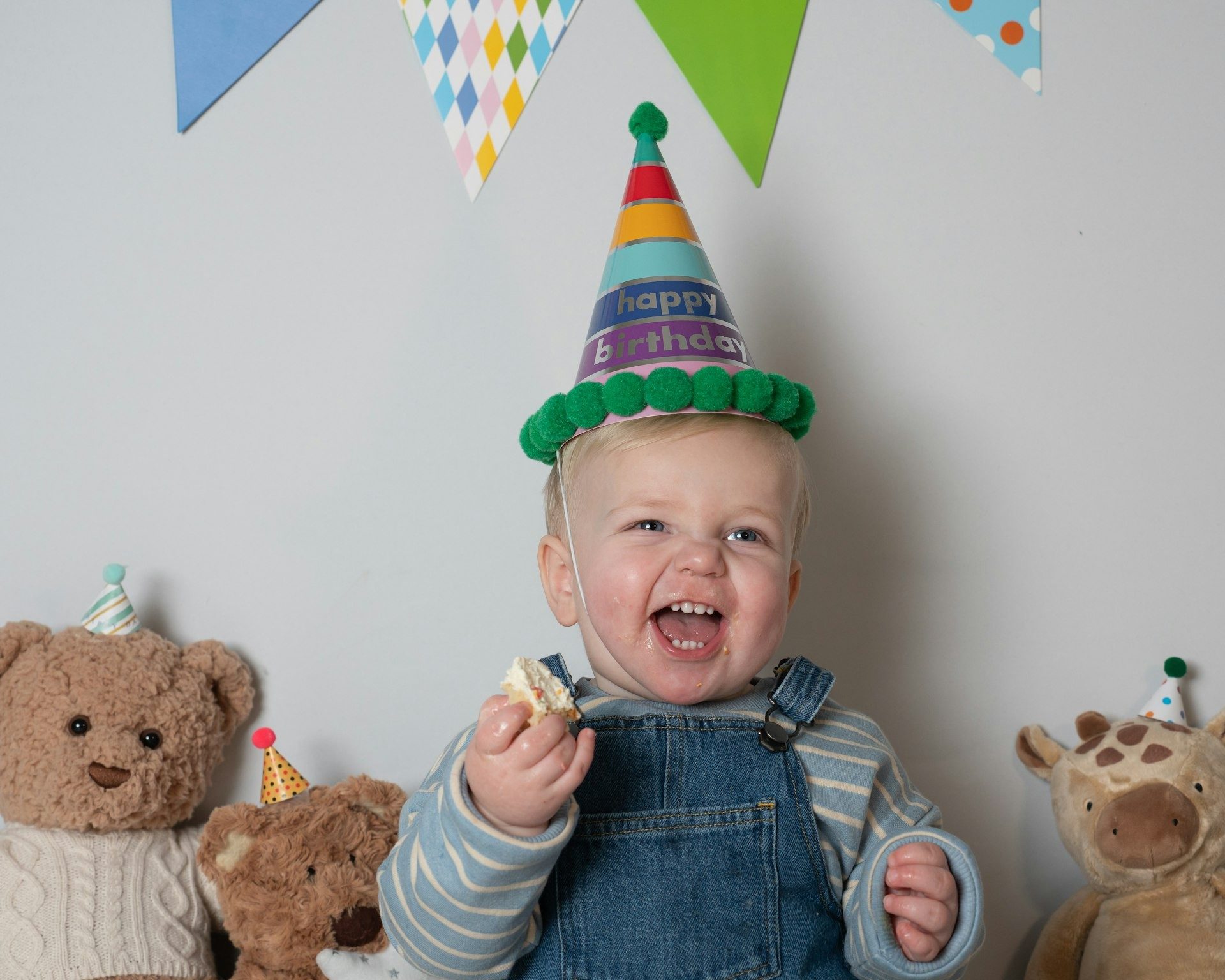Toddler laughs with a handful of birthday cake