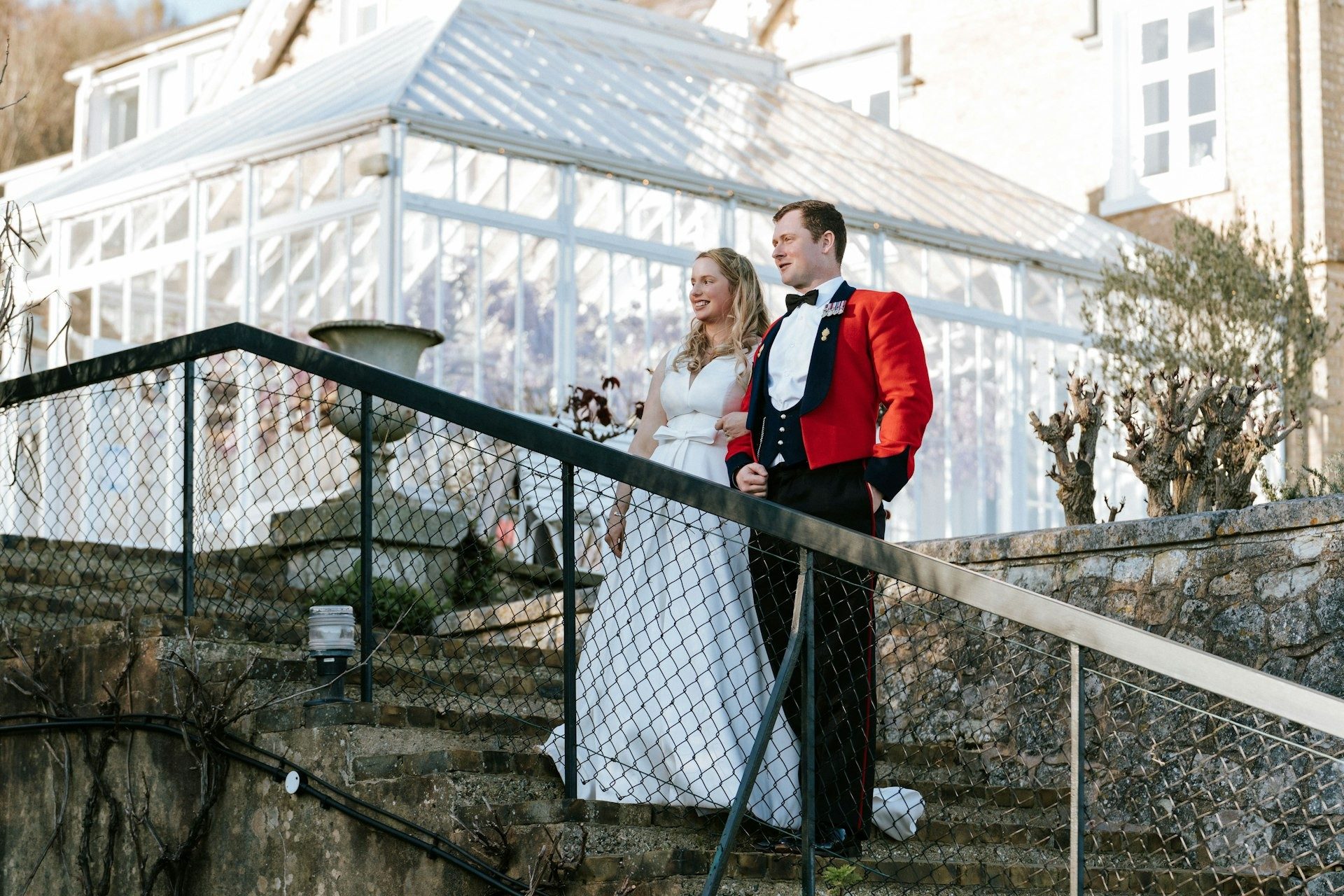 Bride and groom on the steps beside a glass conservatory