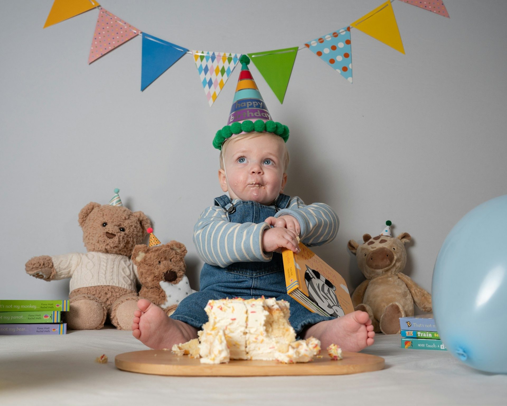 Baby in a party hat with a first birthday cake