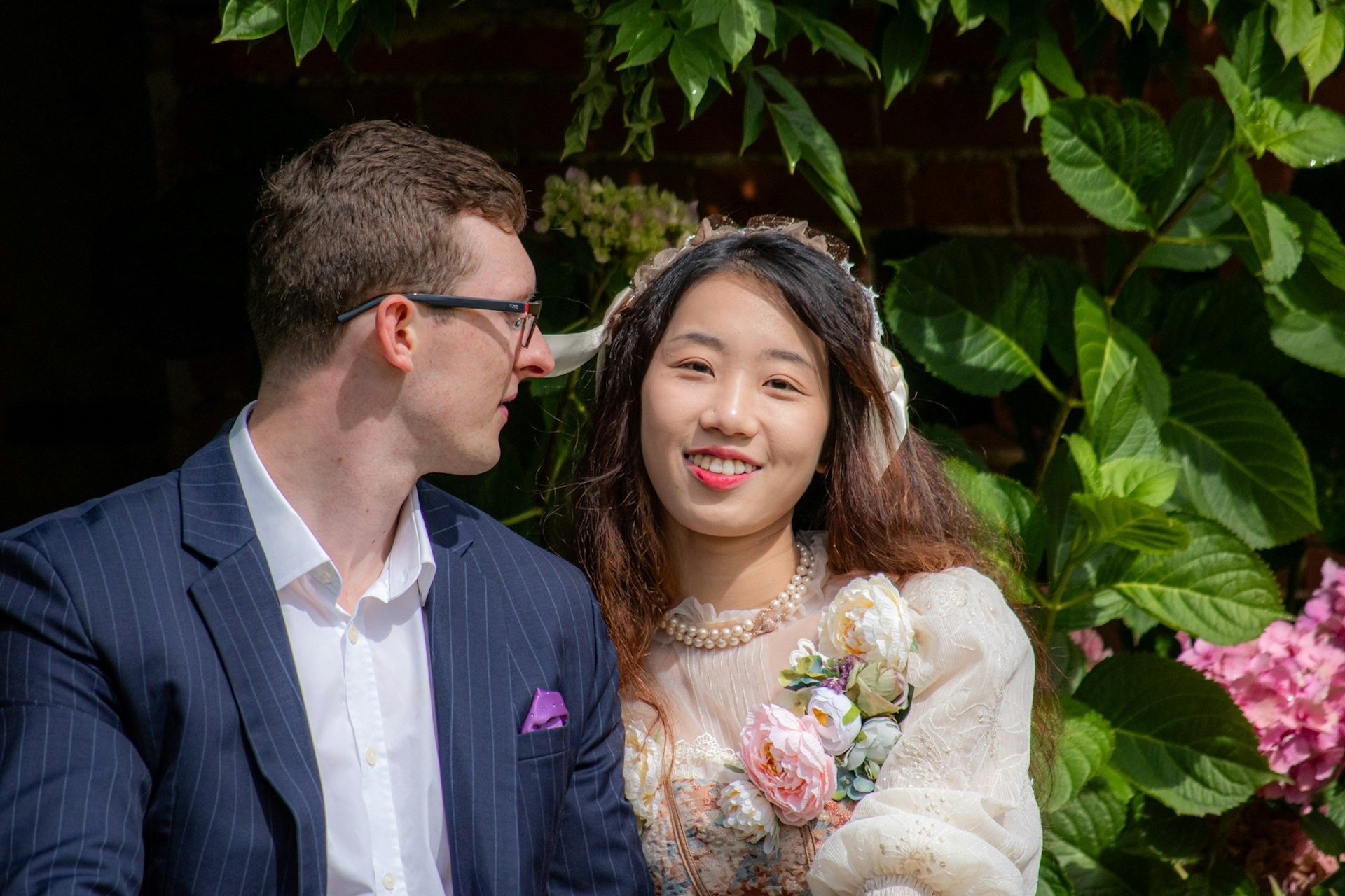 Bride and groom smile together in the garden