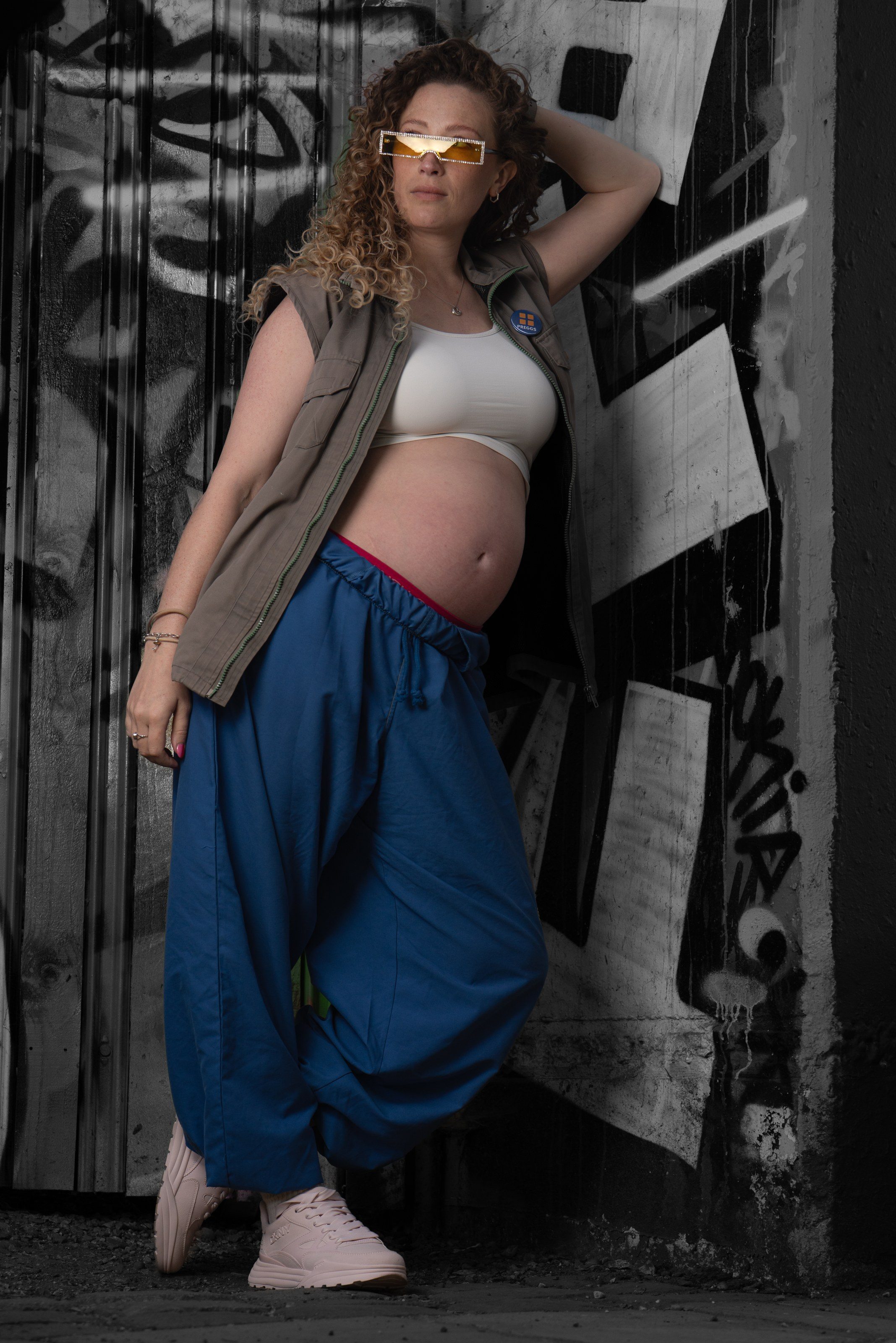 Model in a waistcoat and wide trousers poses in a graffiti doorway