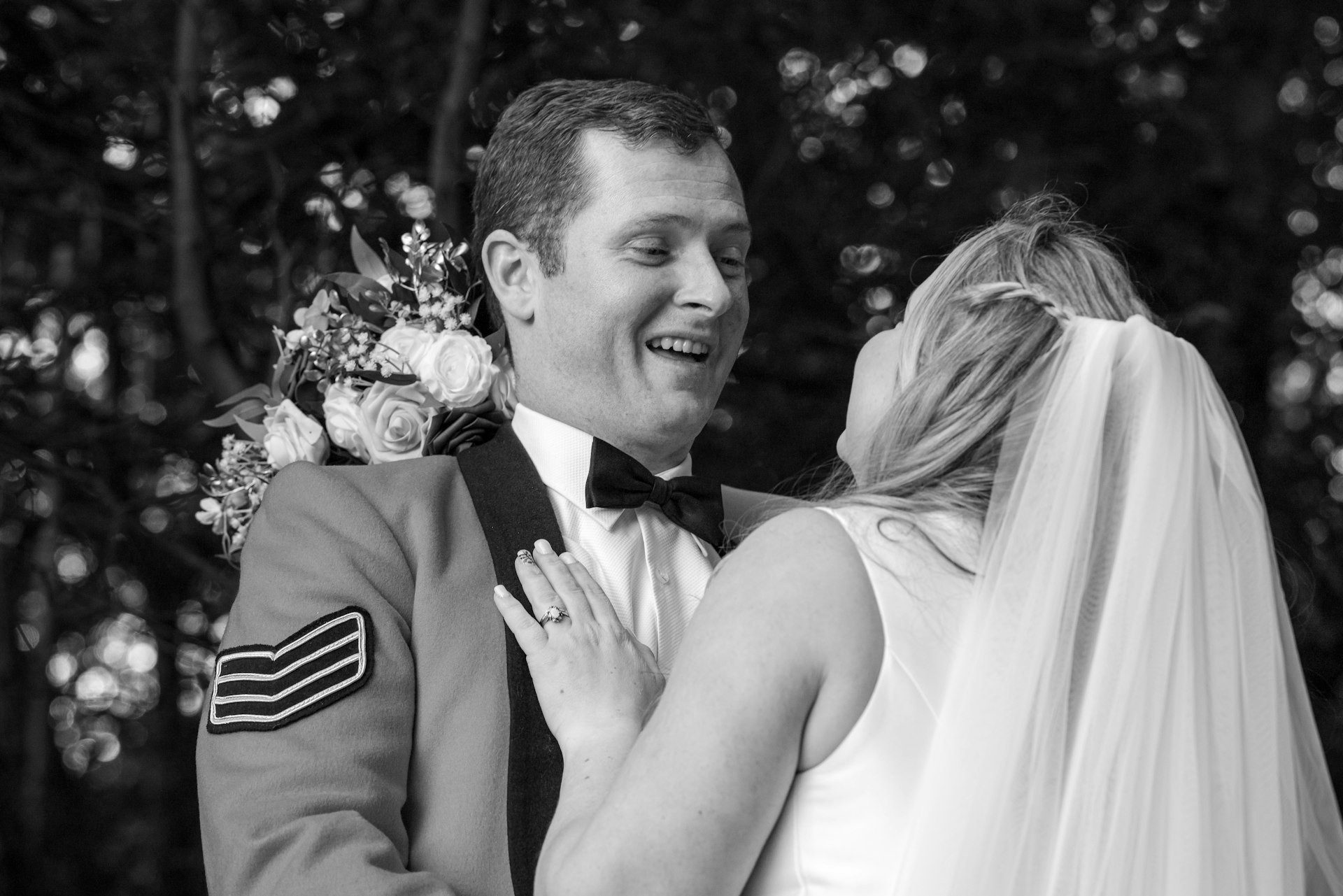 Groom laughs with his bride, in black and white