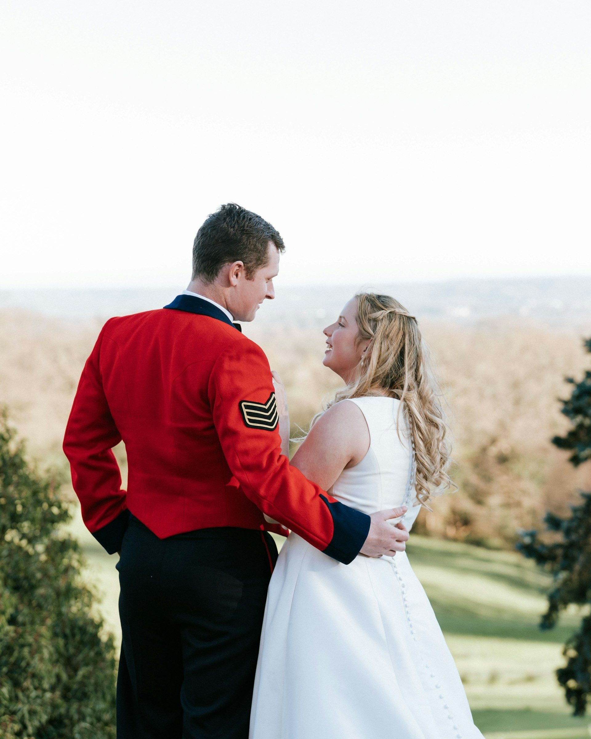Bride and groom share a quiet moment on a hillside lawn