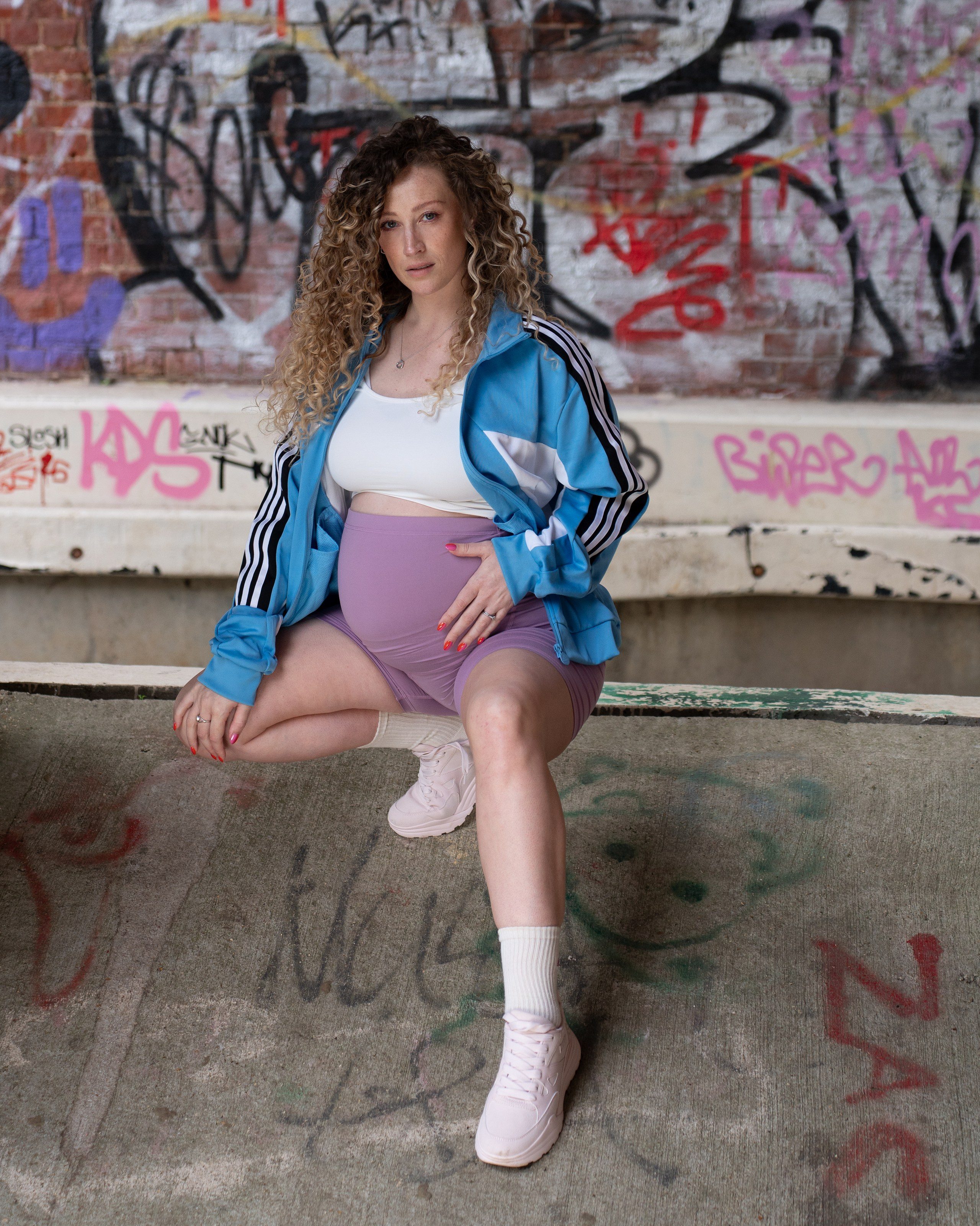 Model sits on a concrete ledge in front of a graffiti wall