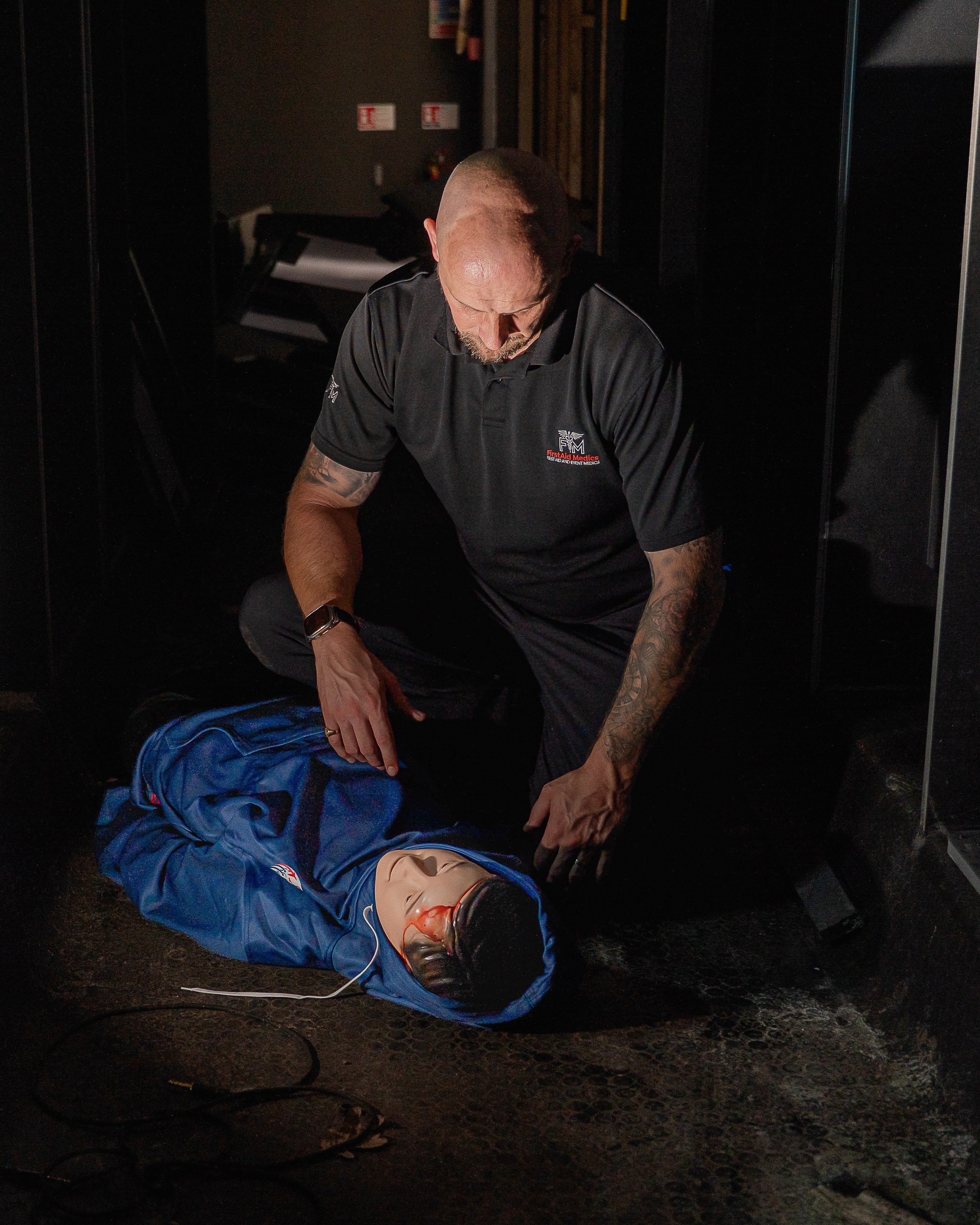 Instructor tends to a casualty in a darkened bus