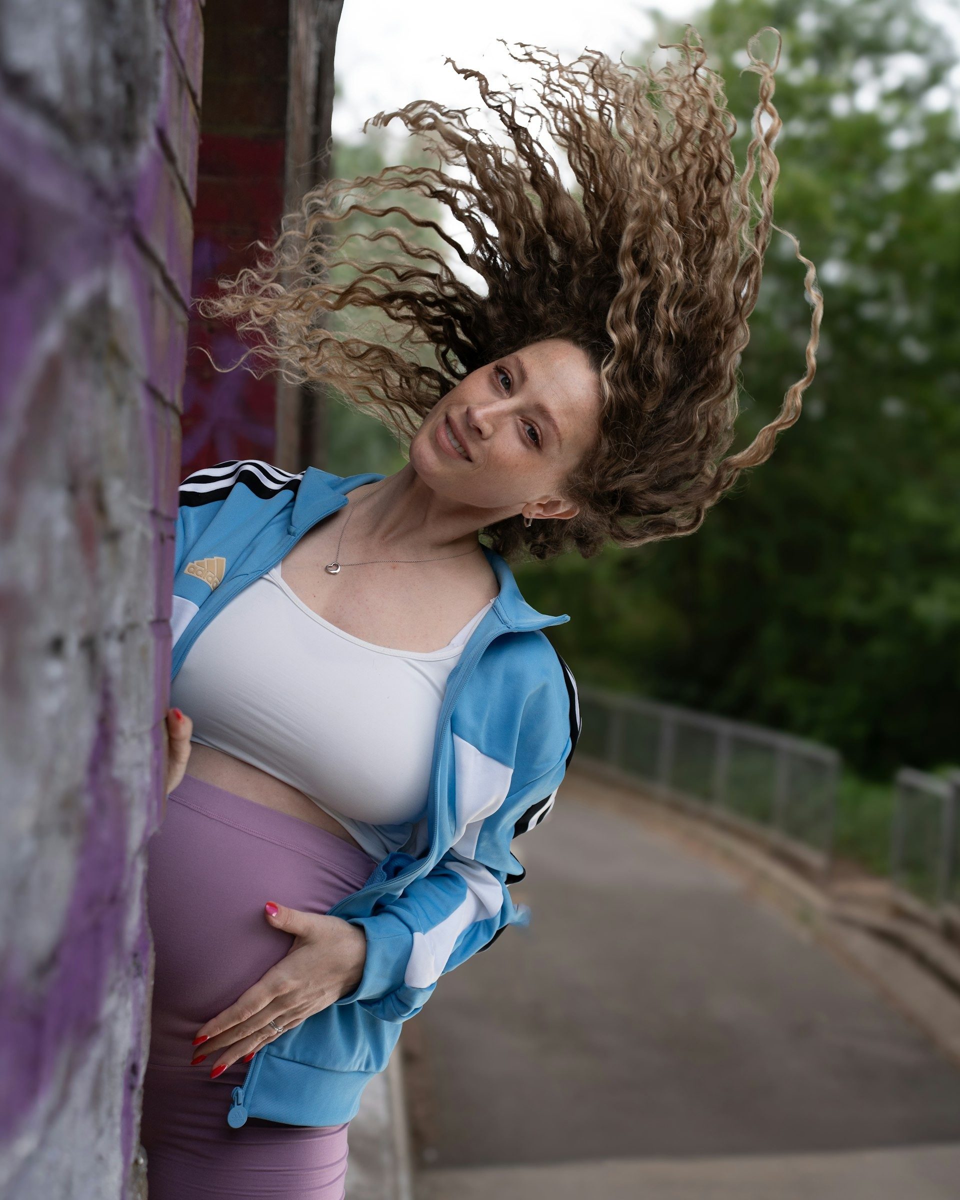 Expectant mother flicks her hair on a woodland path