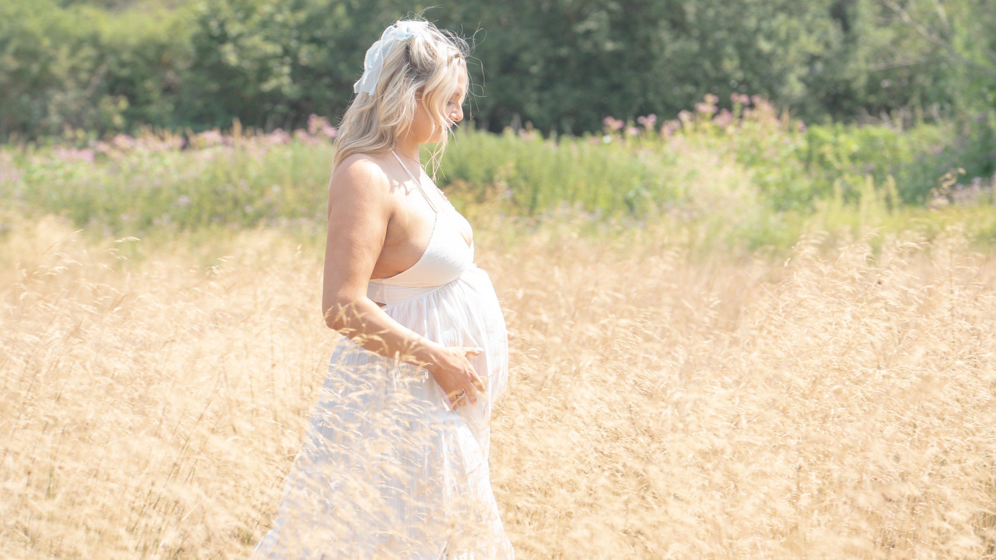 Expectant mother walks through a sunlit meadow