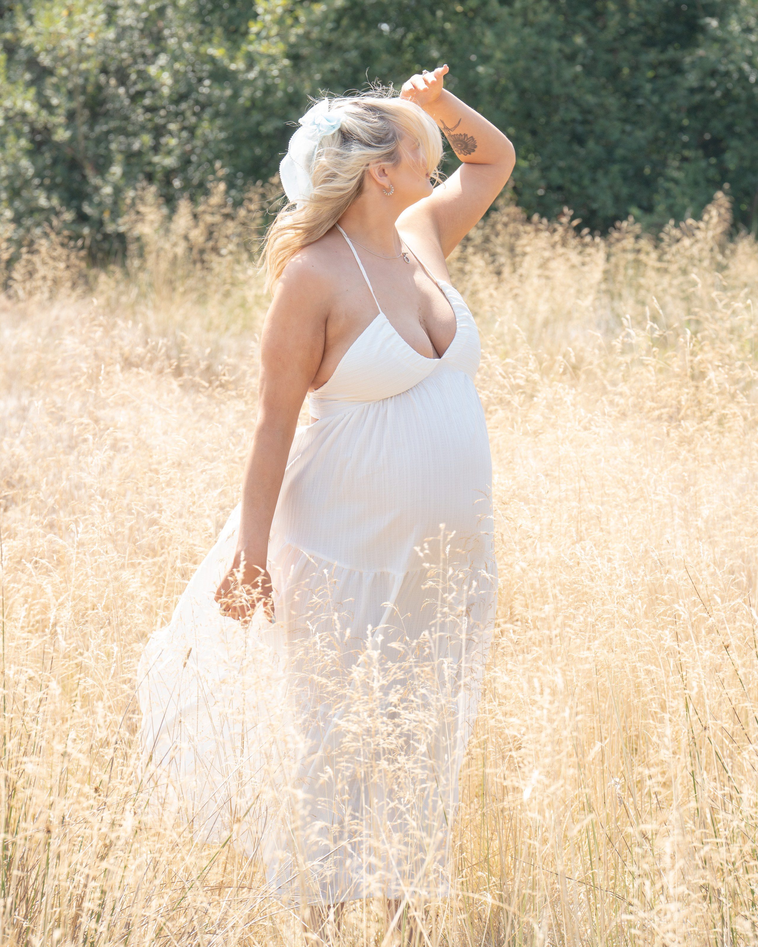 Expectant mother in a white dress in a summer meadow