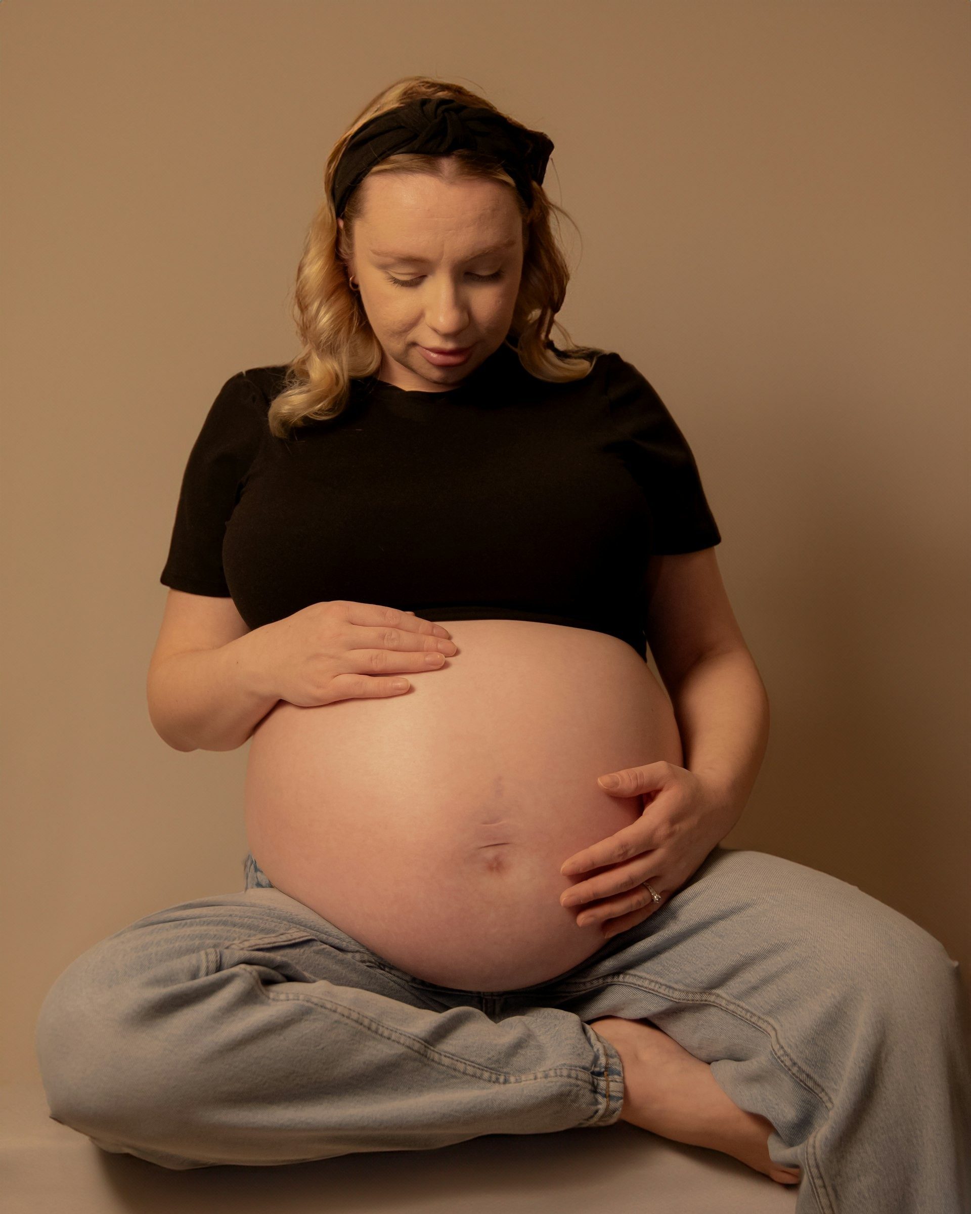 Expectant mother cradles her bump in the studio