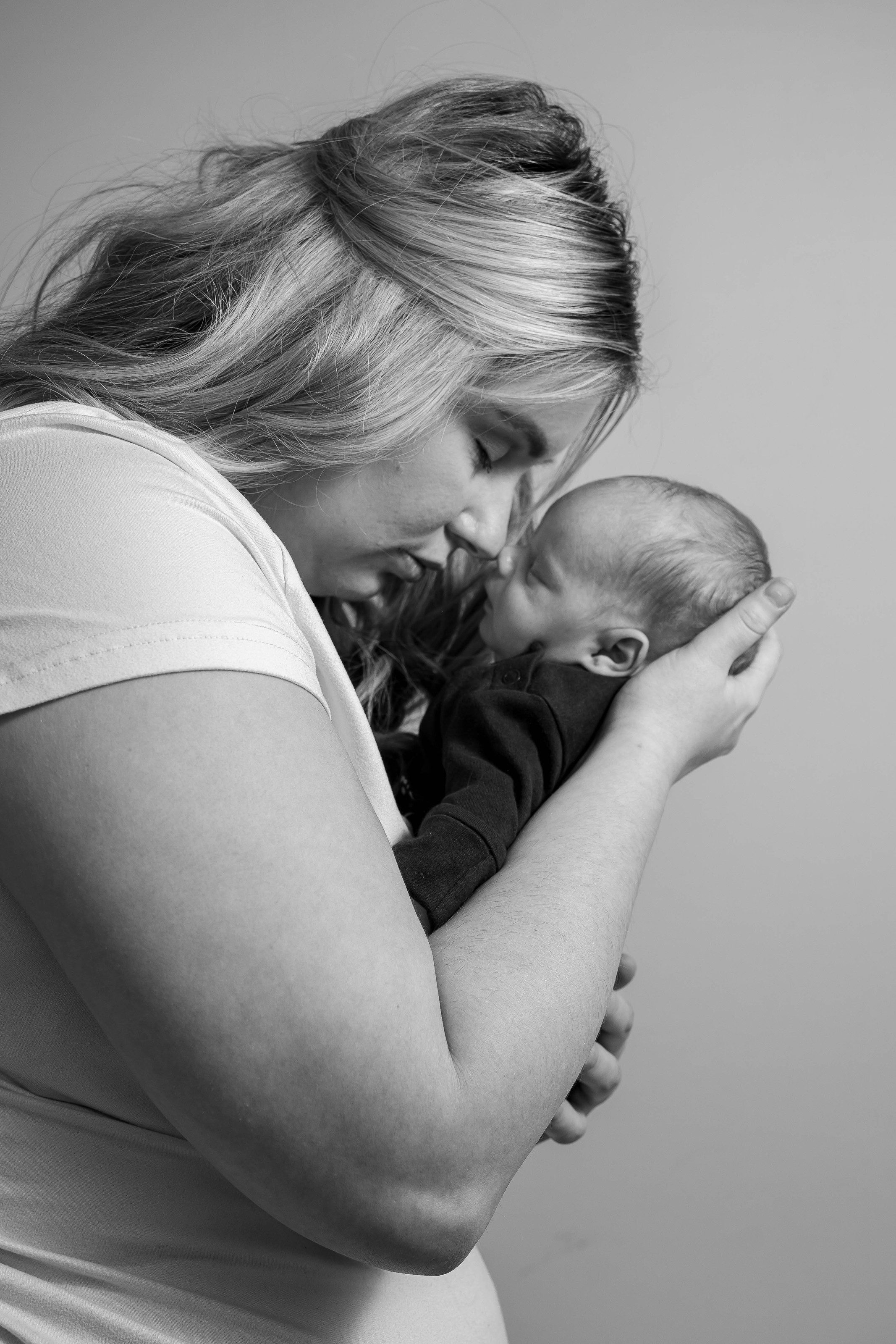 Mother kisses her newborn, in black and white