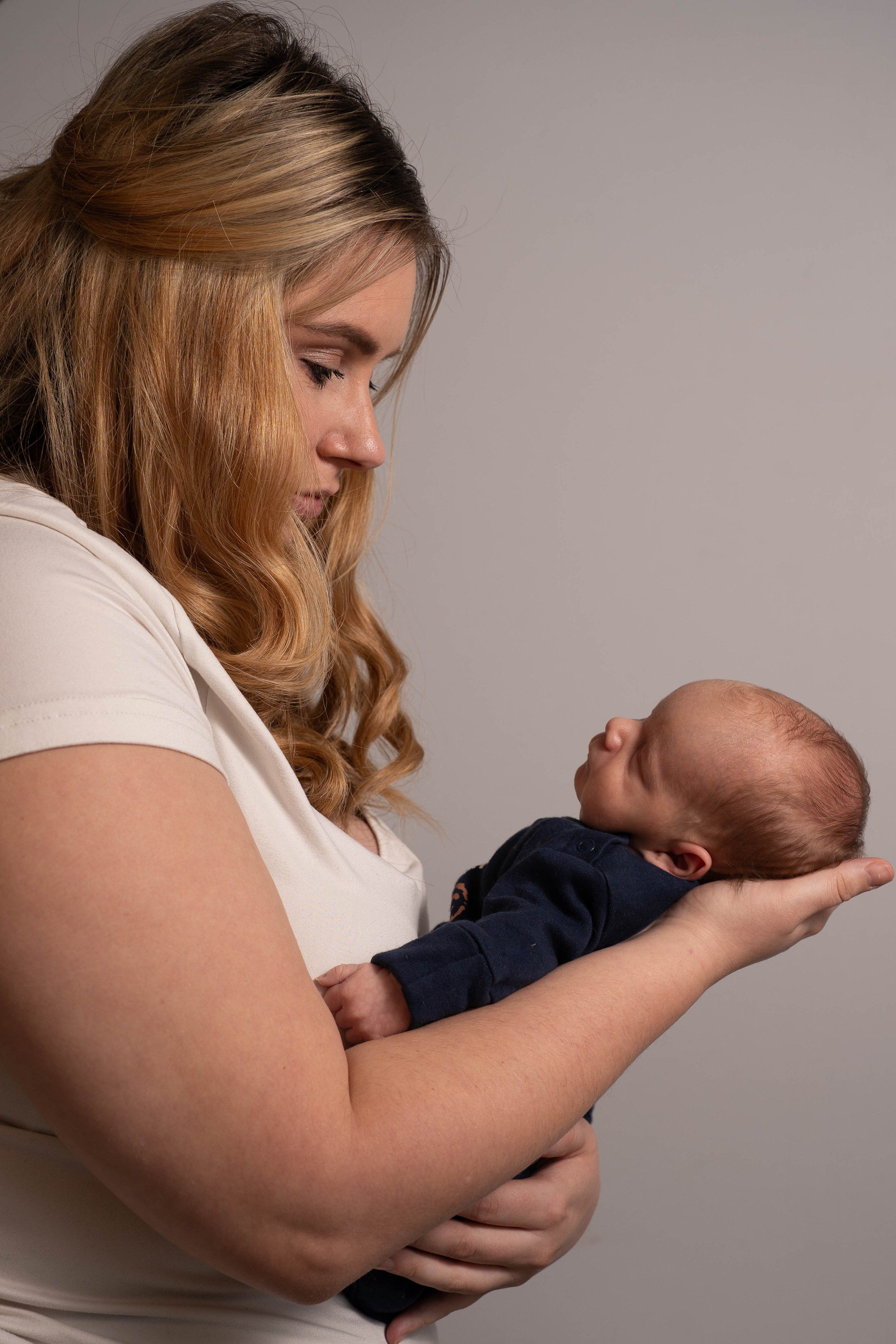 Mother gazes down at her newborn son in the studio