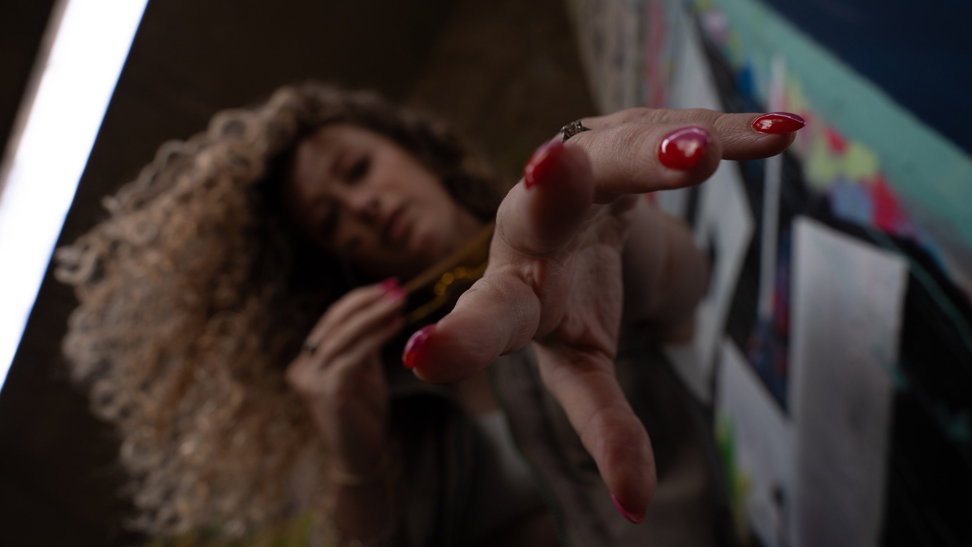 Model studies her nails beneath a graffiti-covered underpass