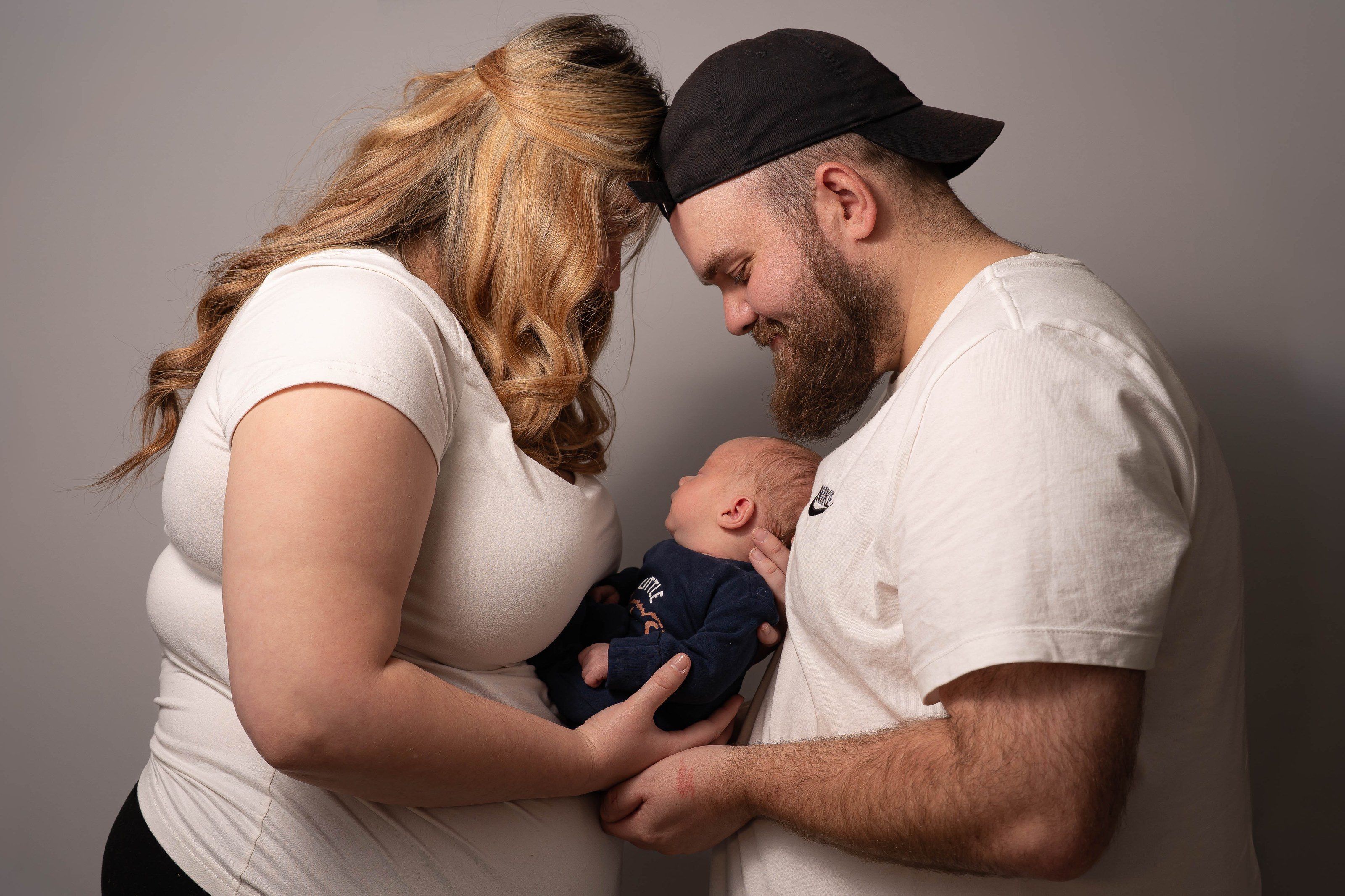 New parents hold their newborn son between them