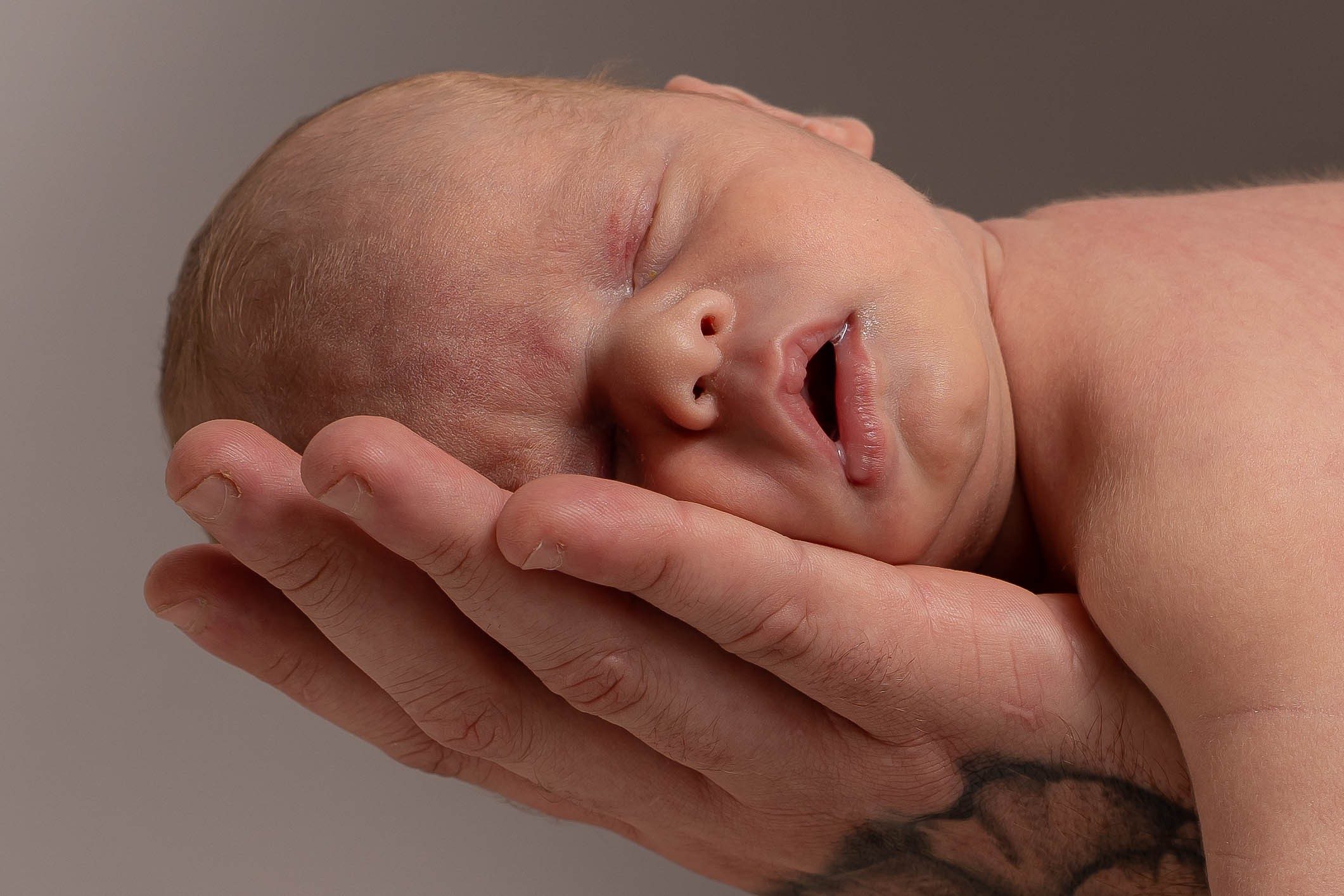 Newborn baby cradled in a father’s hands