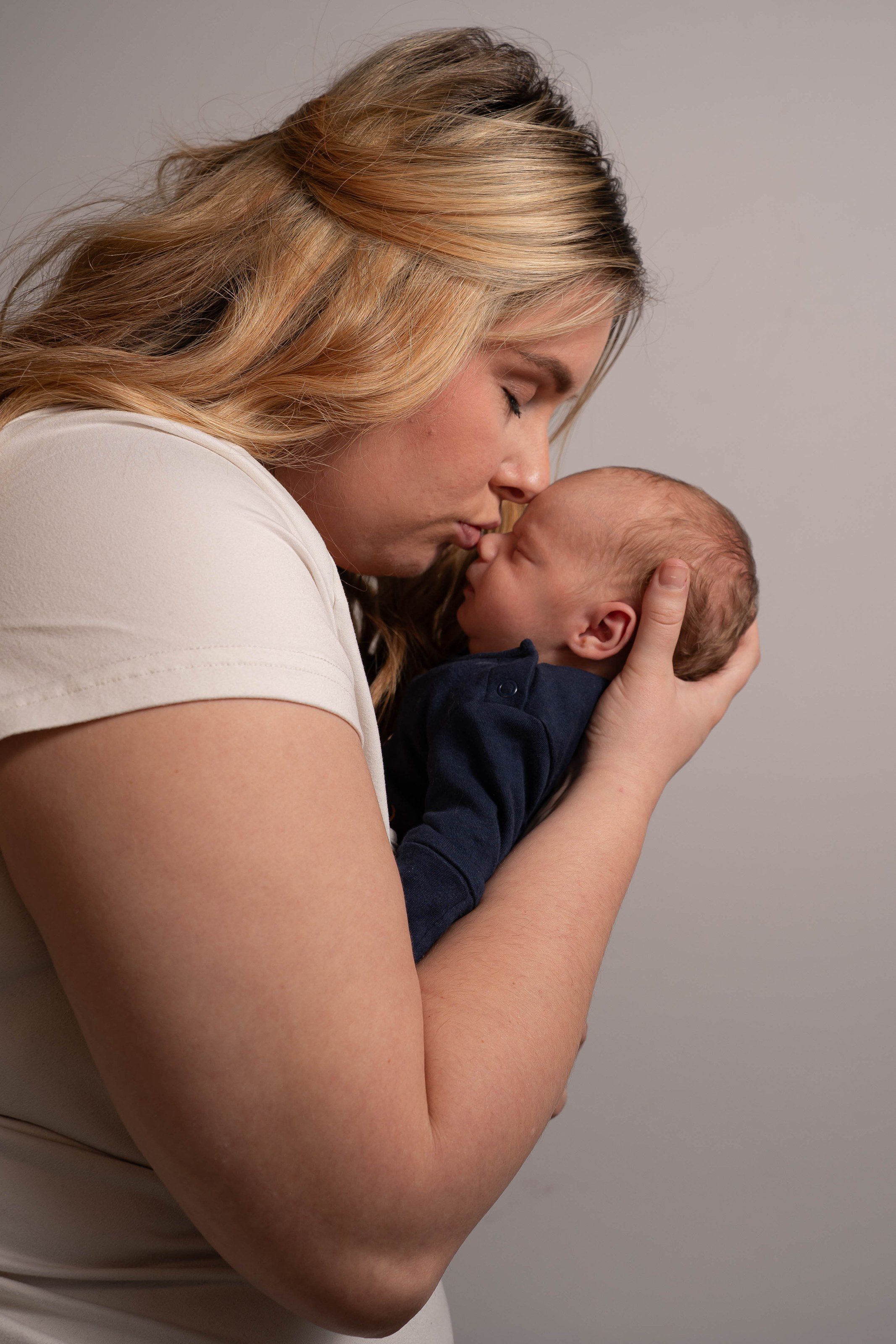 Mother kisses her newborn son’s forehead