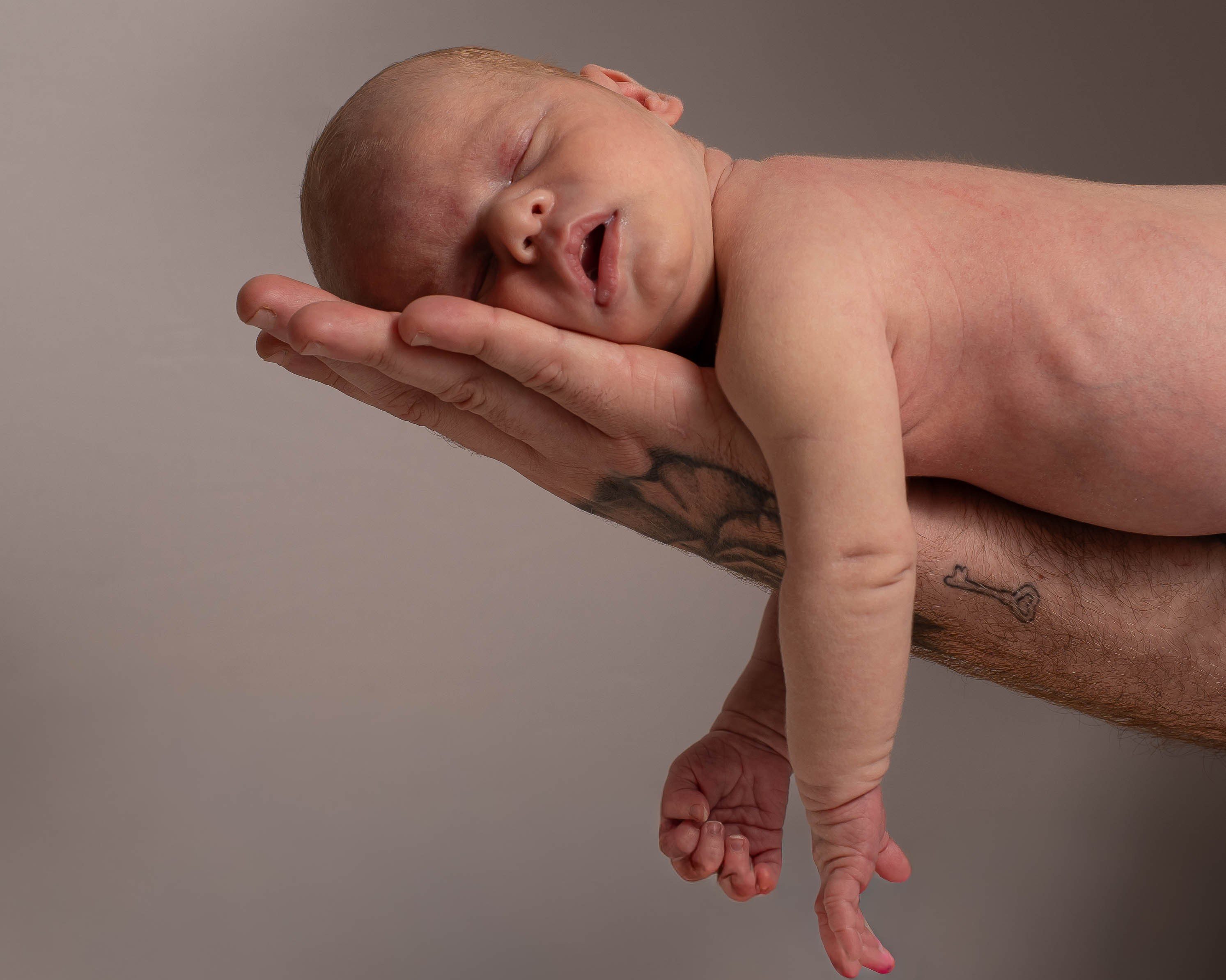 Newborn asleep along his father’s forearm