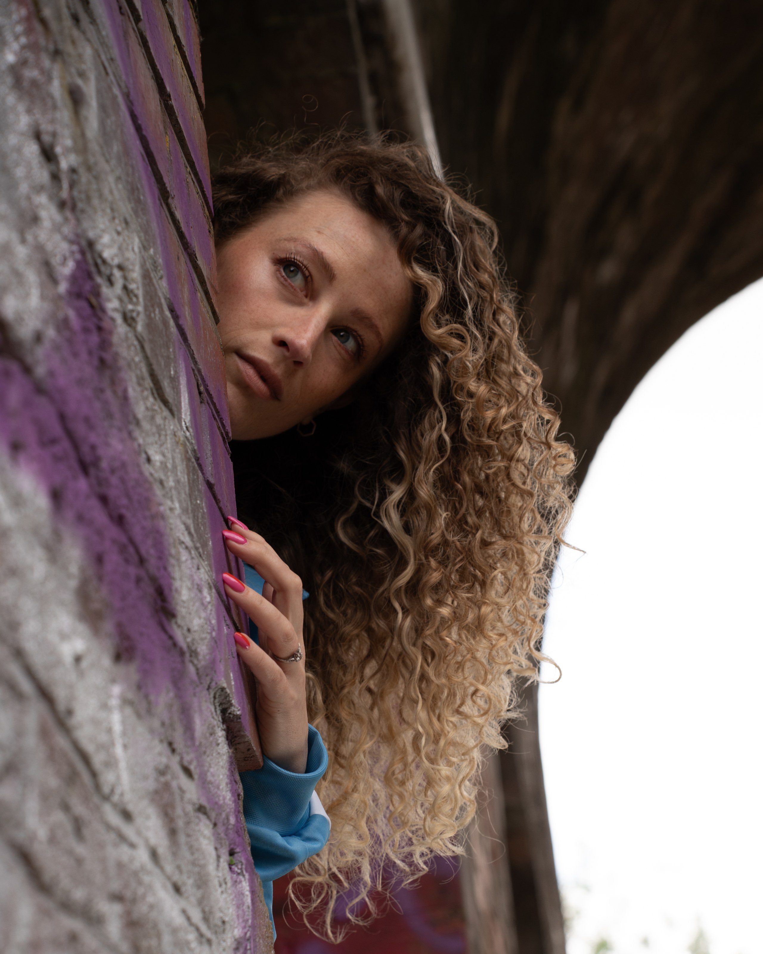 Model peers around a graffiti-covered pillar