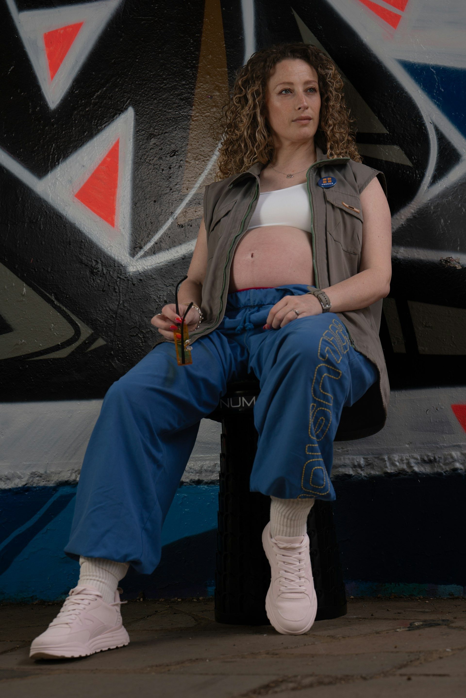 Woman in streetwear sits beneath a graffiti wall