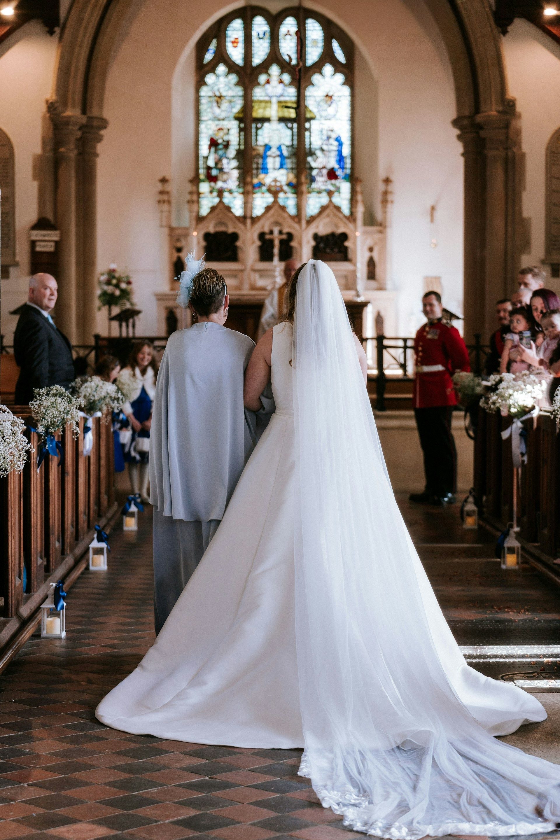 The bride’s long veil trails down the church aisle