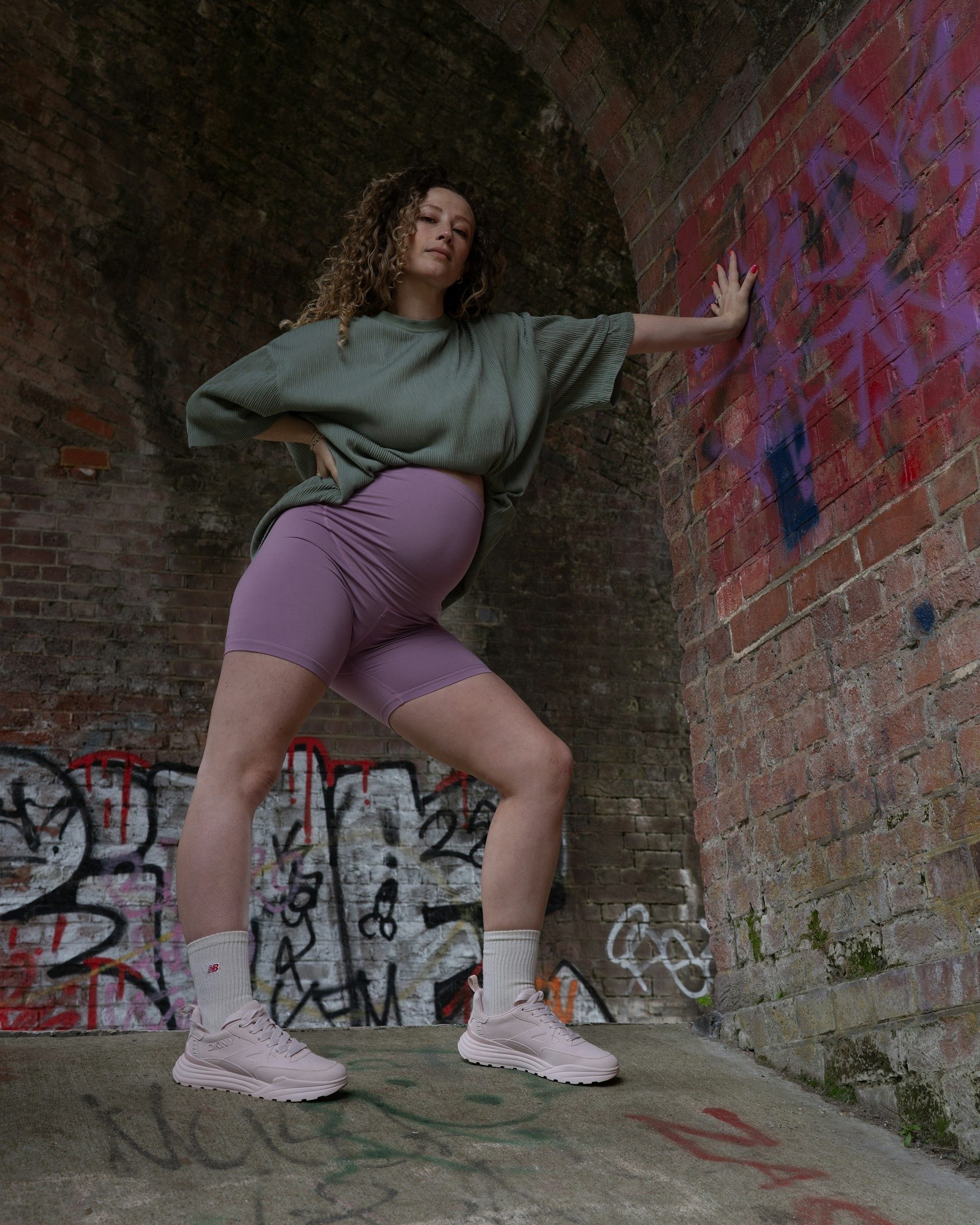 Woman stretches an arm across a graffiti wall