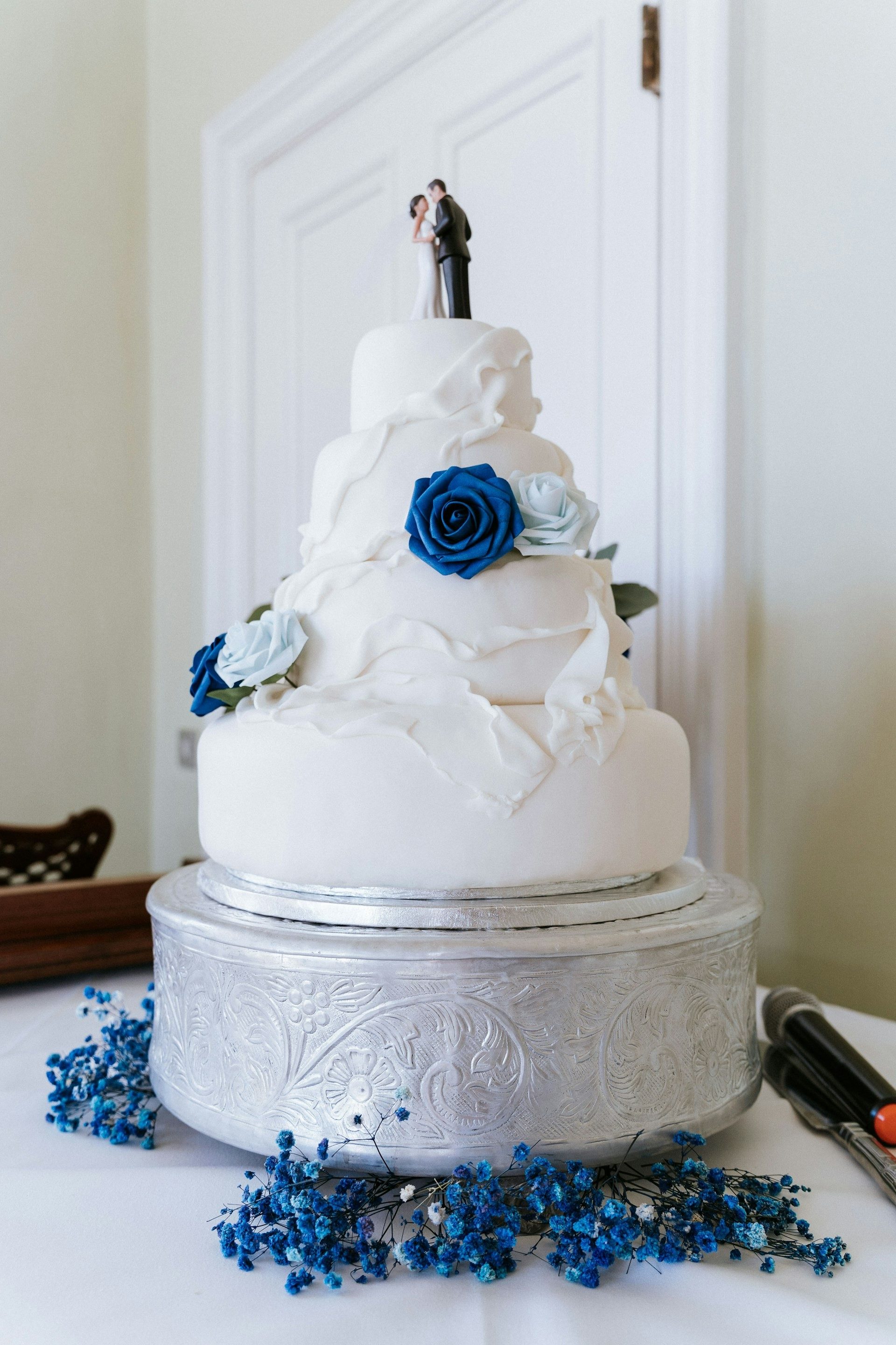 Three-tier white wedding cake decorated with blue roses